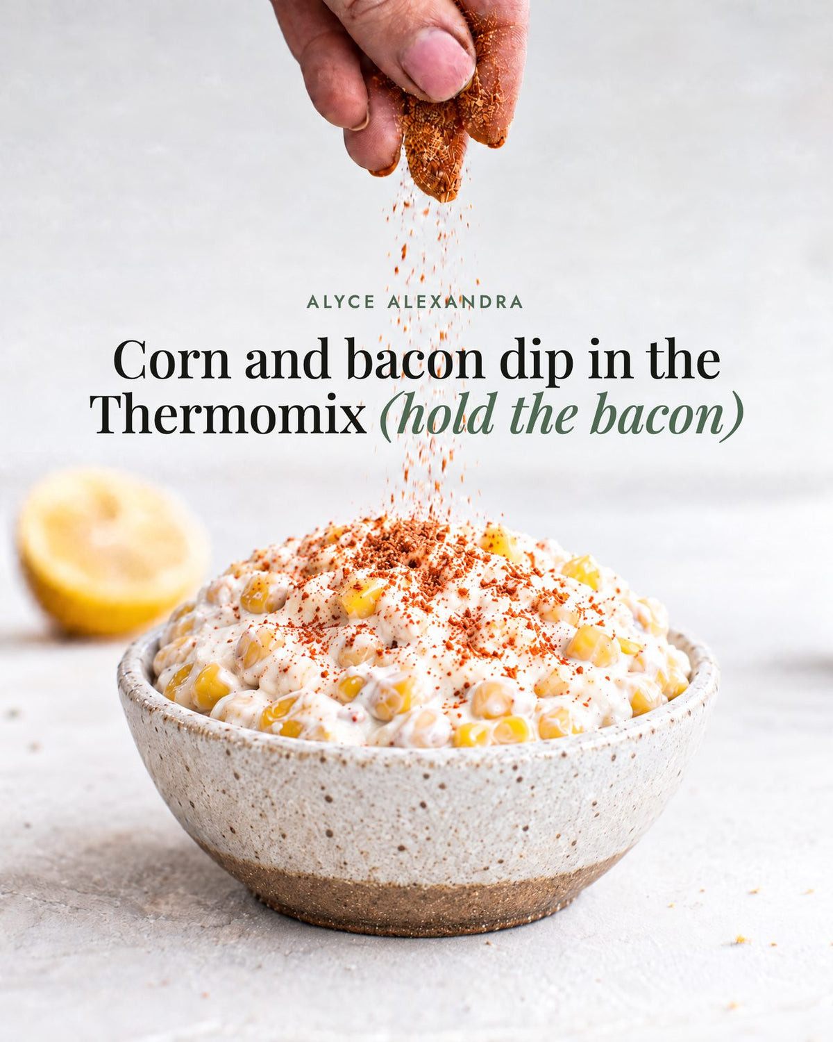 Hand sprinkling No-Bacon Bacon Salt over a speckled ceramic bowl of corn and bacon dip made in the Thermomix, with the headline Corn and bacon dip in the Thermomix (hold the bacon)