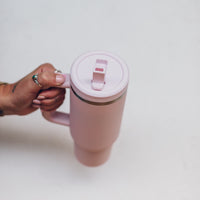 Blush pink 1L Insulated Tumbler held by the handle with the flip-top lid closed, shown from above