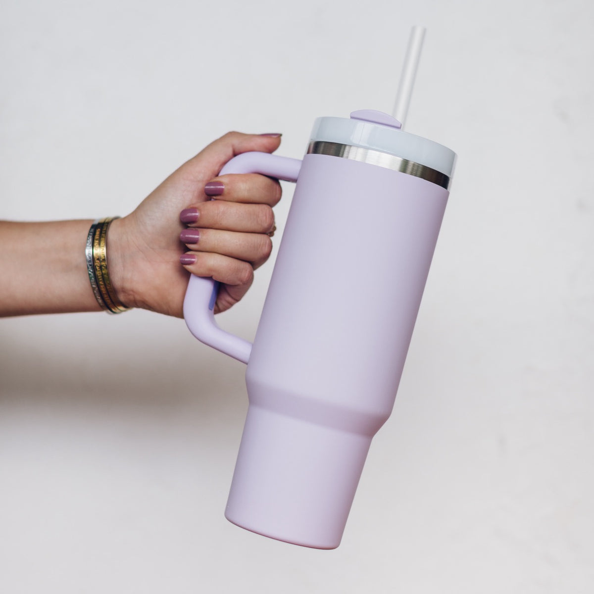 Lilac 1L Insulated Tumbler held by the handle with the straw lid fitted