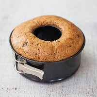 Golden fruit ring cake baked in the 2-in-1 Springform Pan and still sitting in the tin, with the springform clasp visible on the side