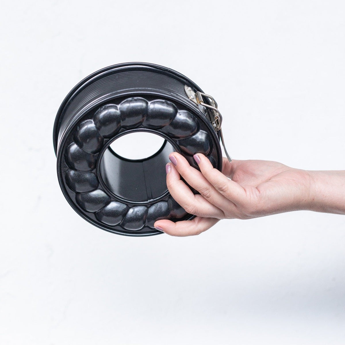 Hand holding the 2-in-1 Springform Pan tilted to show the depth of the fluted ring mould inside