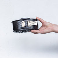 2-in-1 Springform Pan held side on with the springform clasp closed, showing how the tin releases