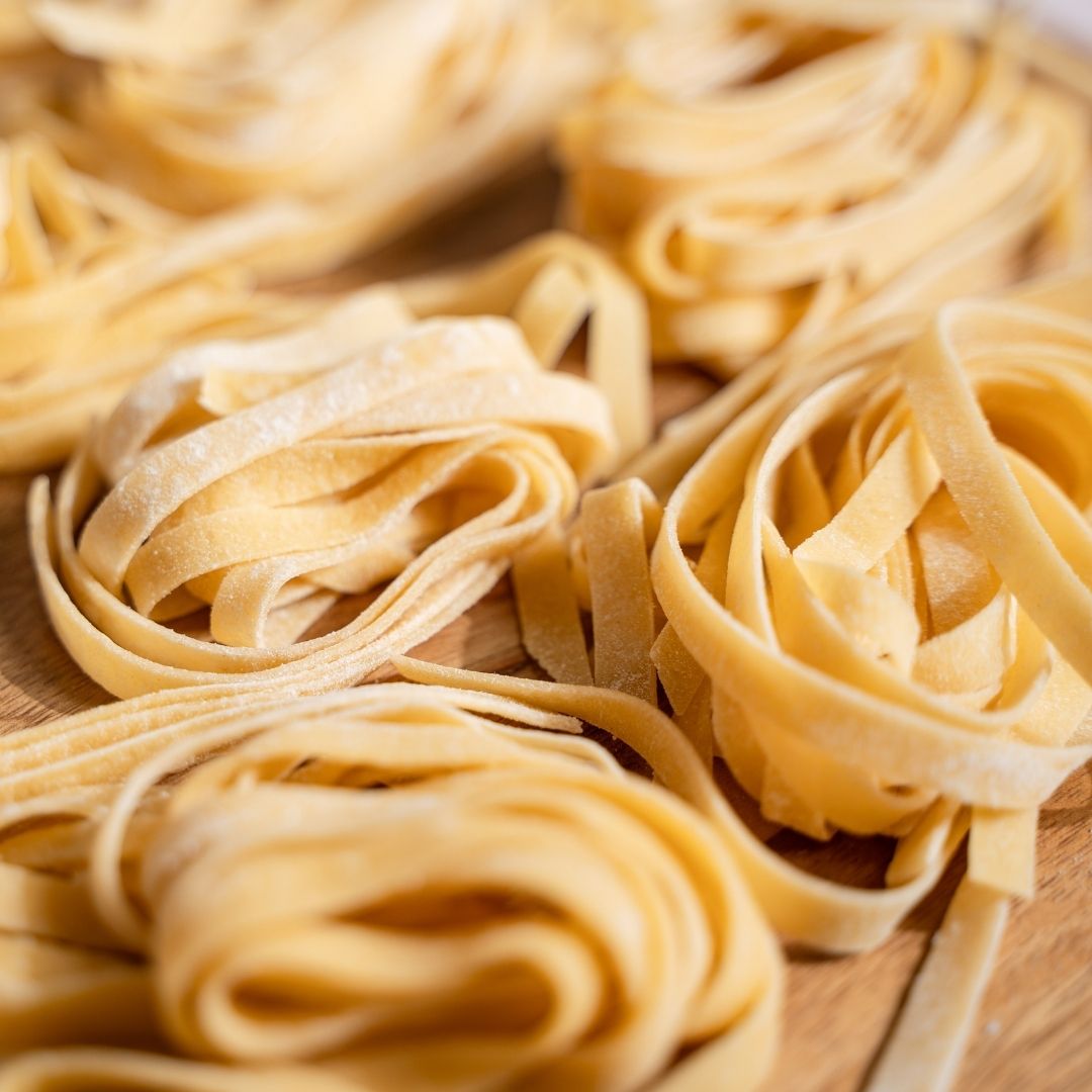 Nests of freshly cut fettuccine piled together, shown close up