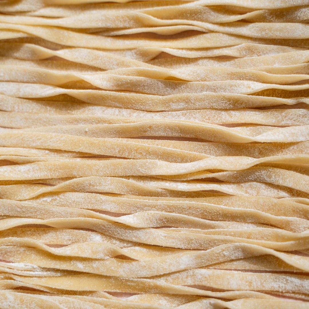 Overhead close-up of freshly rolled fettuccine ribbons laid out in rows