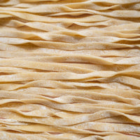 Overhead close-up of freshly rolled fettuccine ribbons laid out in rows