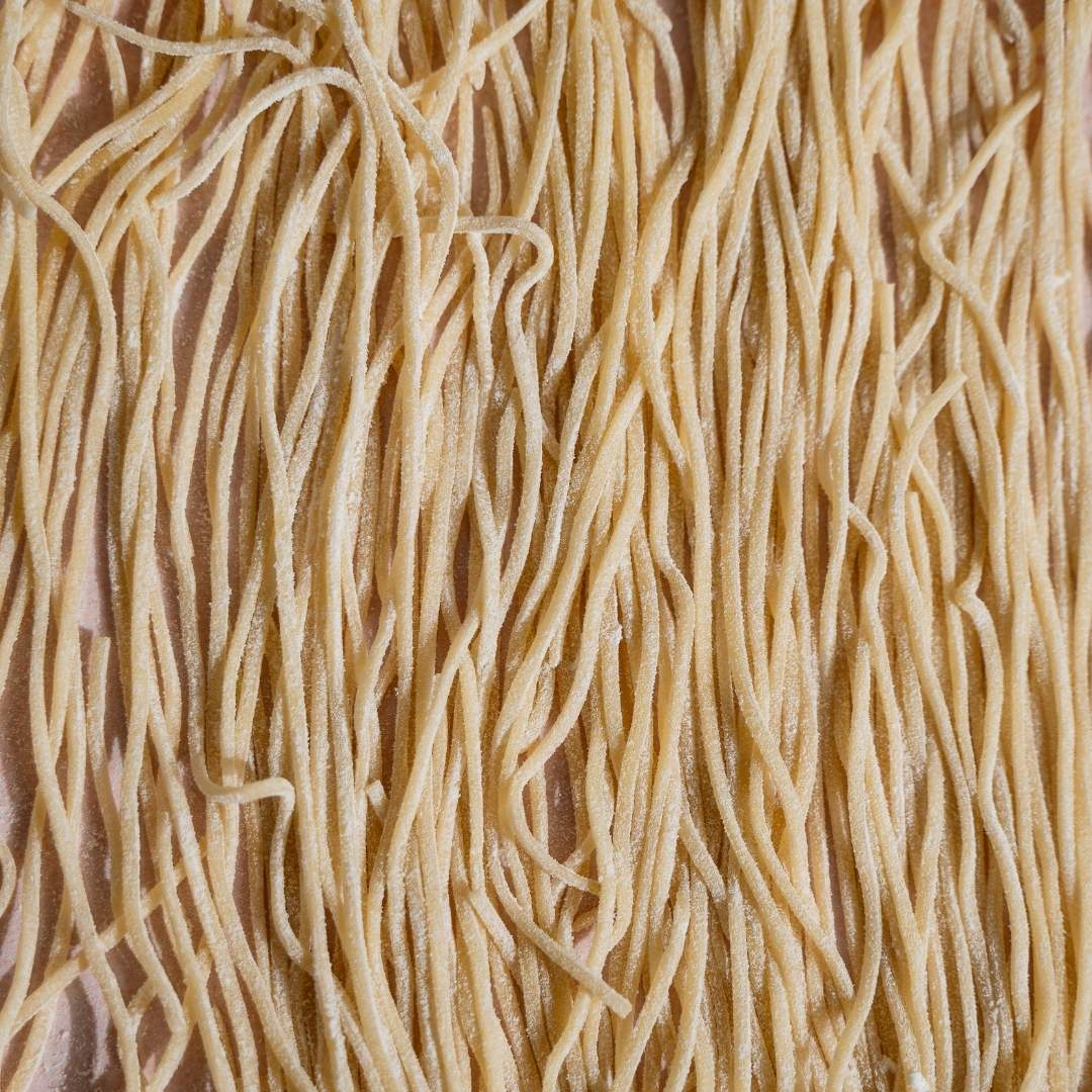 Close-up of long strands of freshly cut spaghetti hanging to dry