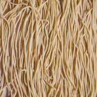 Close-up of long strands of freshly cut spaghetti hanging to dry