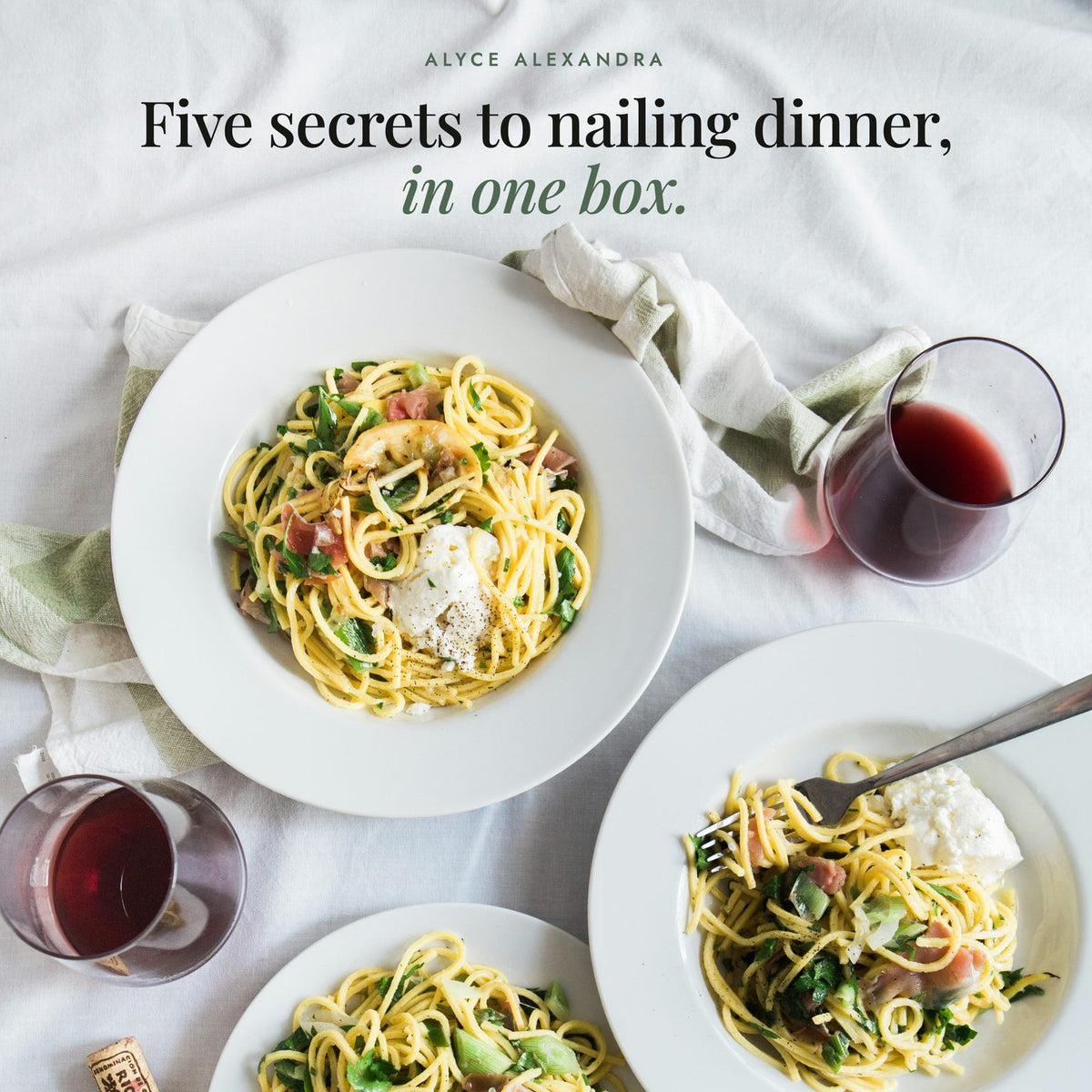 Table set with bowls of spaghetti with prosciutto, burrata, parsley and lemon beside glasses of red wine; Alyce's Flavour Bombs Starter Pack is five secrets to nailing dinner, in one box