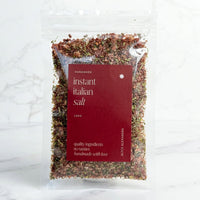 Alyce's Instant Italian Salt in a clear 100g packet with a deep red label, the tomato and herb flecked blend visible through the front