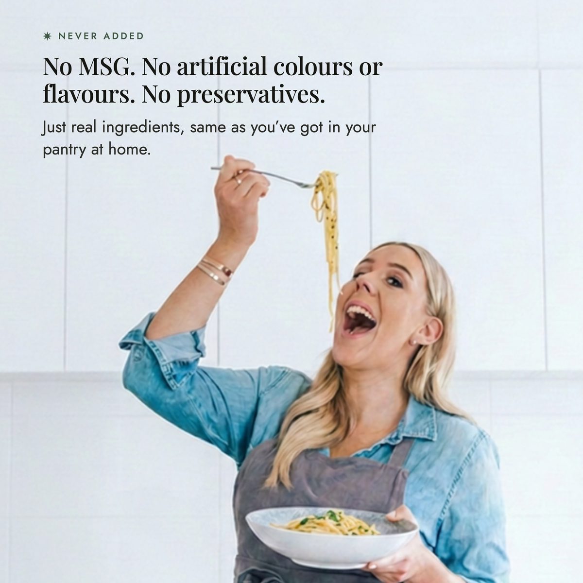 Alyce laughing in her white kitchen as she lifts a forkful of spaghetti above a bowl of pasta; never added to Organic Flavour Bomb Salt: no MSG, no artificial colours or flavours, no preservatives, just real ingredients like the ones in your pantry at home