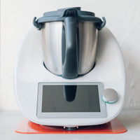 Thermomix sitting on a red Appliance Mat, showing the colour options available