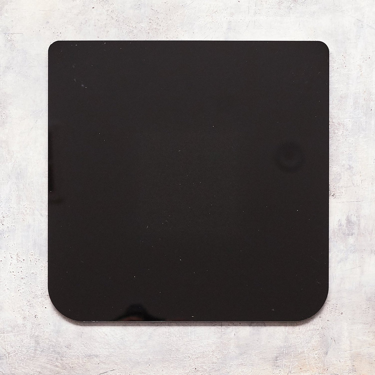 The Appliance Mat on its own, a thin square black mat with a small notch on one edge