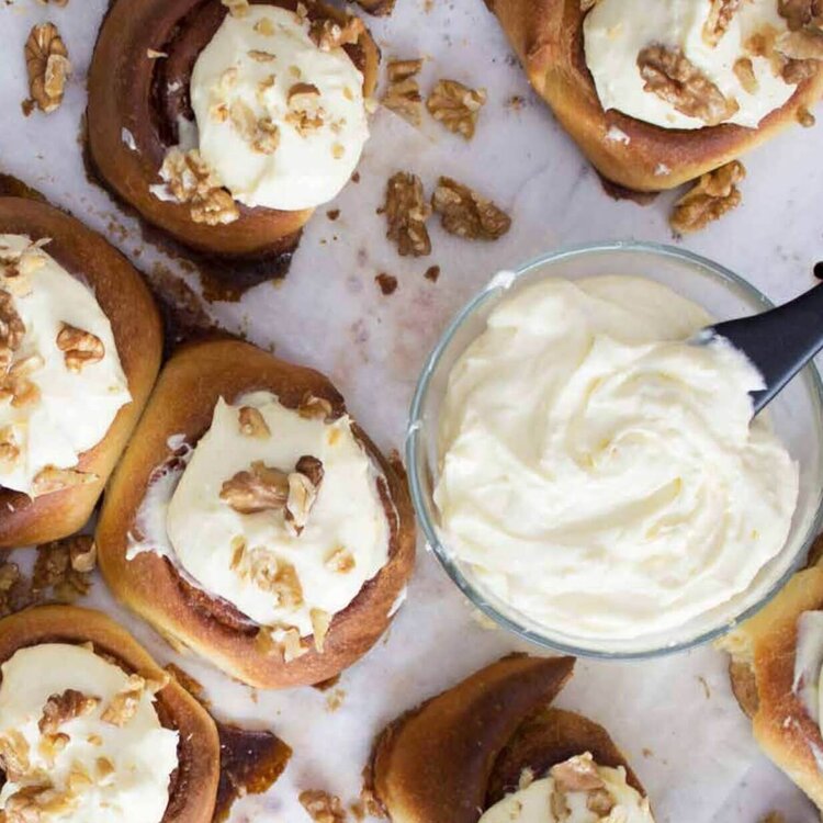 Overhead tray of cinnamon scrolls topped with cream cheese icing and chopped walnuts, from the Bread Class Booklet