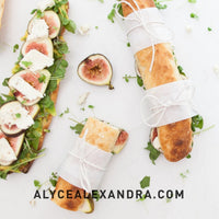 Baguettes and open sandwiches topped with figs, cheese and greens, tied with string ready to carry