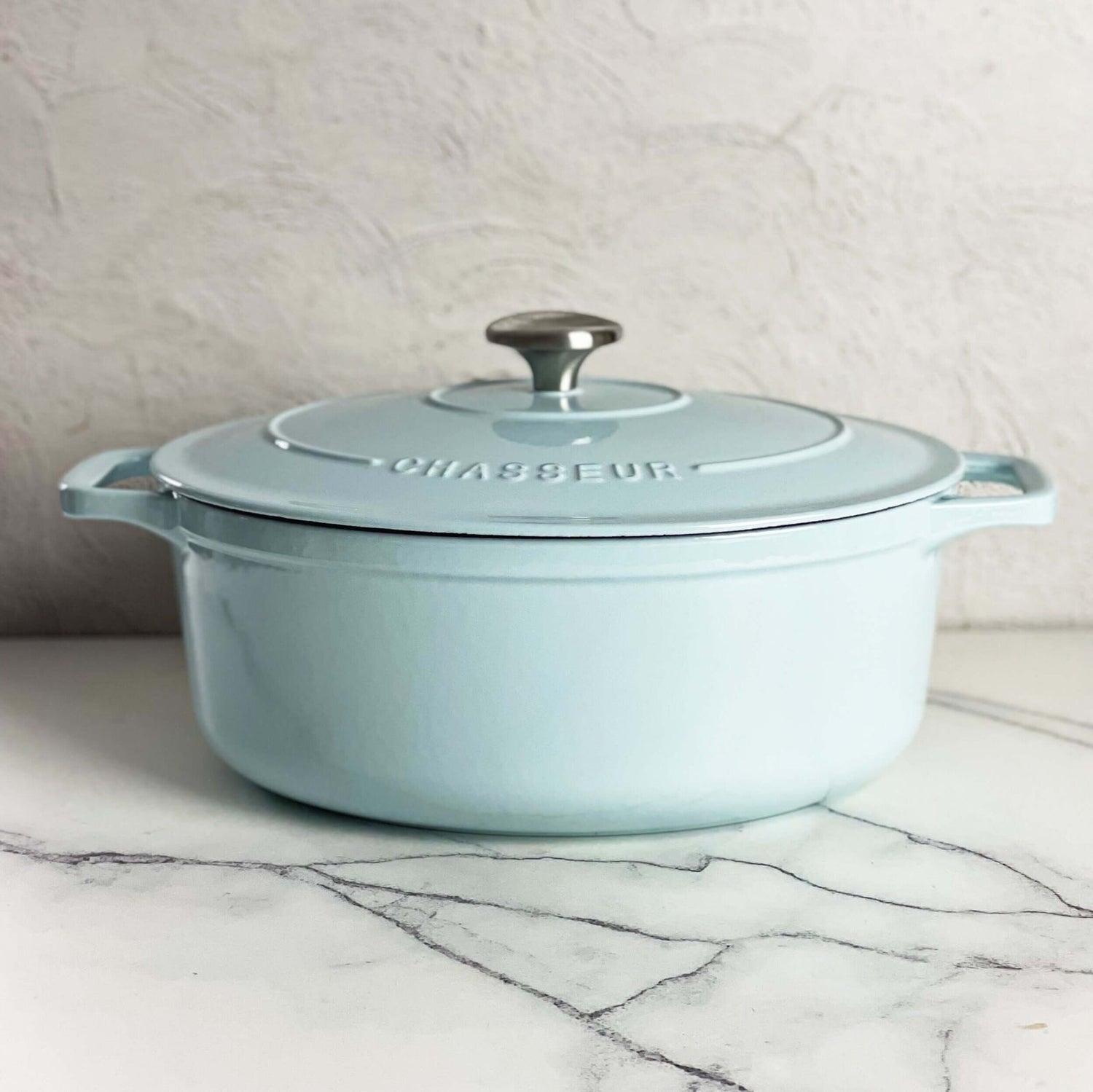 Duck egg blue Chasseur cast iron oval Dutch oven with its lid on, on marble