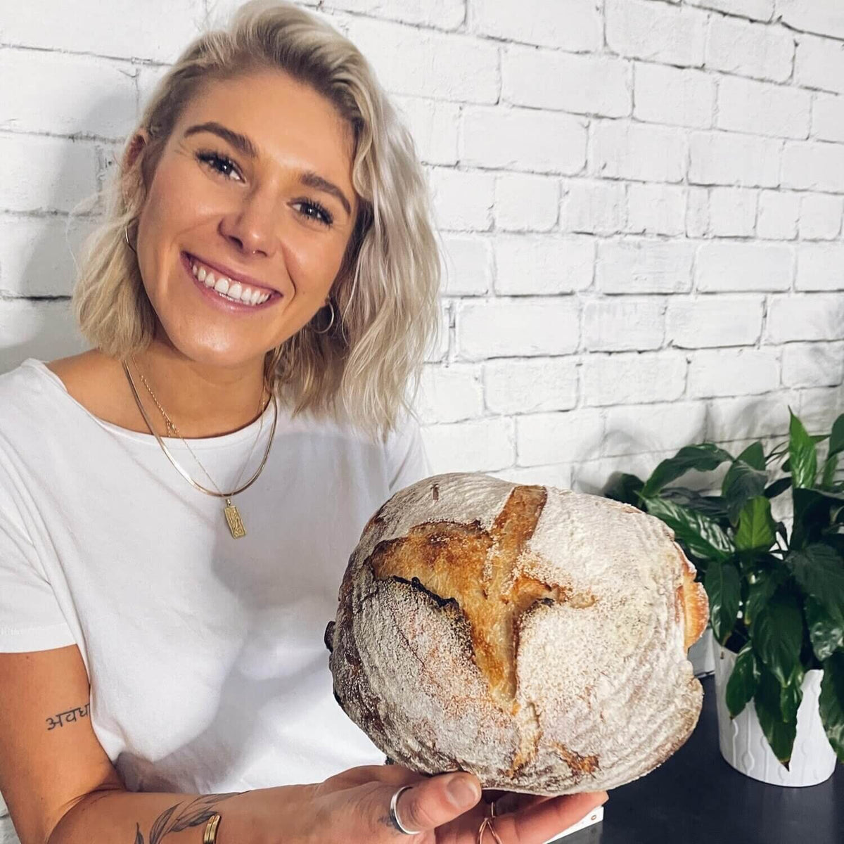 Woman holding a scored round sourdough loaf of bread baked in the cast iron Dutch oven