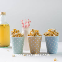 Cups of caramel popcorn with paper straws and a bottle of cordial, from the Champagne Breakfast Class Booklet