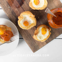 Baked egg tarts in pastry cases with runny yolks, served with relish on a wooden board, from the Champagne Breakfast Class Booklet