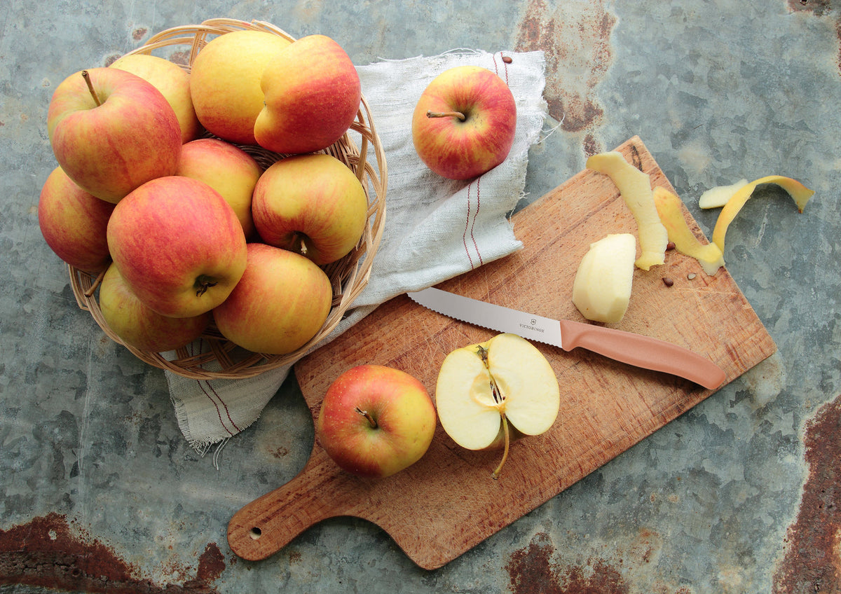Classic Serrated Knife on a wooden board with sliced and whole apples
