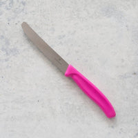 Classic Serrated Knife with a pink handle laid on concrete