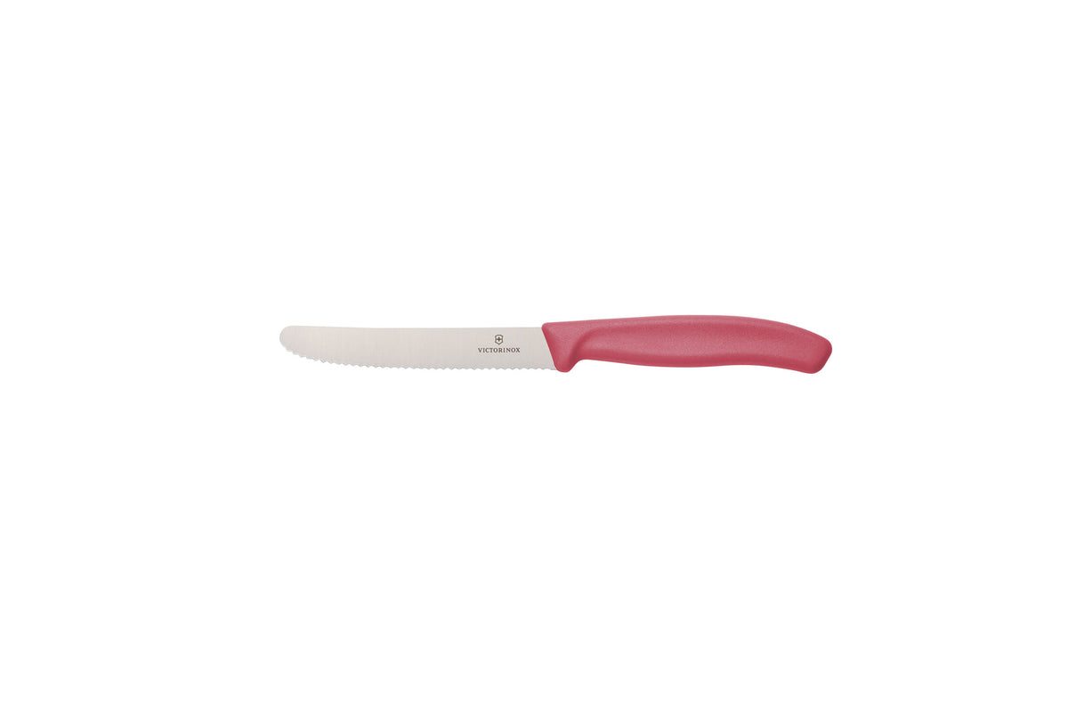 The Classic Serrated Knife shown side on against a white background, with a pink moulded handle and a Victorinox-branded stainless steel blade with fine serrations and a rounded tip