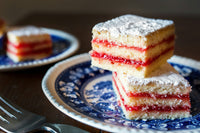 Stacked squares of jam and coconut sponge slice on a patterned plate, baked in the Deep Sheet Pan