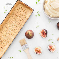 Blind-baked tart shell with a pastry brush, fresh figs and a bowl of cream, from the Desserts Class Booklet