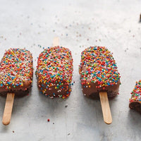 Row of chocolate-coated ice creams covered in hundreds and thousands