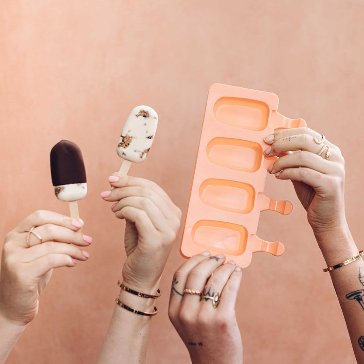Three hands each holding a different ice cream, with an empty mould tray held up alongside