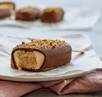 Chocolate-coated ice cream with a crumb topping, cut to show the caramel centre