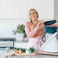 Alyce lifting the Varoma lid off her Thermomix in a styled kitchen with a wooden slide board underneath