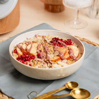 Bowl of porridge topped with pomegranate, nuts and fruit, made from freshly flaked oats