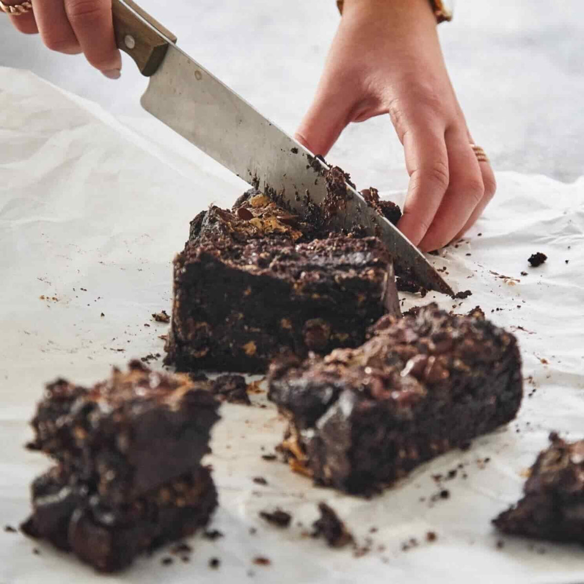 Knife slicing into a dense chocolate brownie slab, from Hearty Vegan Thermo Cooked