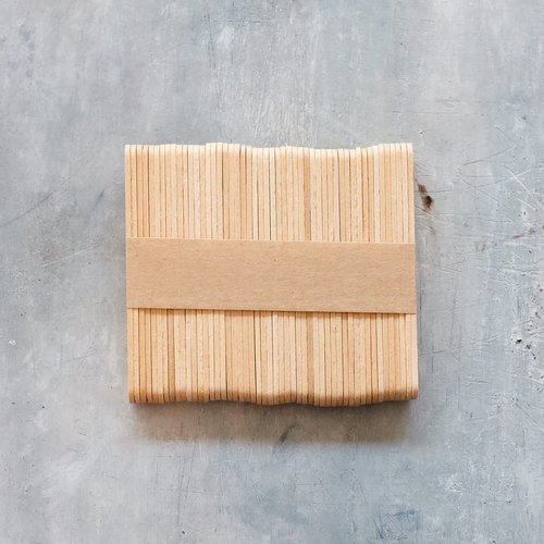Bundle of wooden Ice Cream Sticks banded together on a stone bench