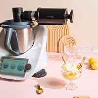 Ice Shaver mounted on a Thermomix in a styled kitchen with shaved ice desserts and ice cubes alongside