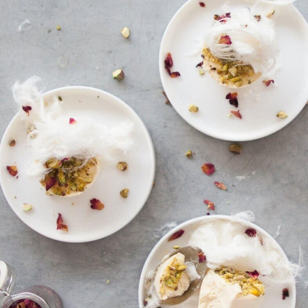 Plates of Indian dessert scattered with rose petals and pistachio, from the Indian Class Booklet