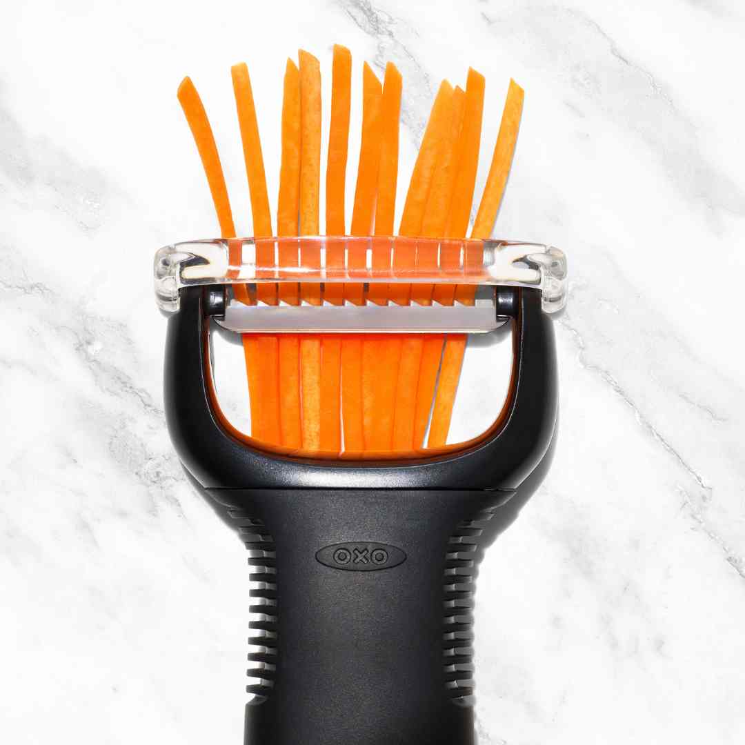 Julienne Peeler shredding a carrot into fine matchsticks on a marble bench