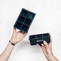 Hands holding two Jumbo Freezer Pods trays, one with its lid on