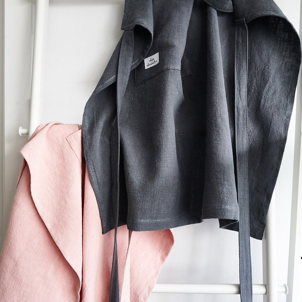 Charcoal Linen Apron hanging on a rail beside a blush pink one