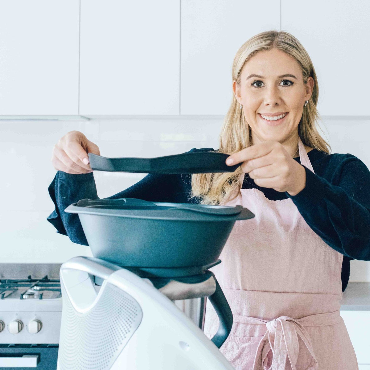 Alyce in a blush pink Linen Apron lifting the Varoma off her Thermomix
