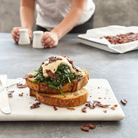 Open sandwich topped with greens and coconut bacon on a board, made with Liquid Smoke