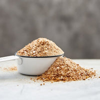 Mug of smoky seasoning powder spilling onto a dark surface, made with Liquid Smoke