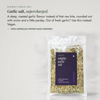 Mighty Garlic Salt packet on a pale bench; garlic salt supercharged, a deep roasted garlic flavour instead of that raw bite, rounded out with onion and a little parsley, use it when you are out of fresh garlic, vegan, from a 100% Australian owned family business