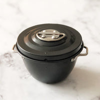 Single Mini Non-Stick Steamer basin with its lid clipped on and side handles, on a marble bench