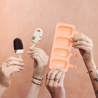 Hands holding mini ice creams beside an empty terracotta mould tray
