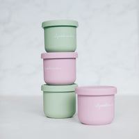 Mini Silicone Pot Containers stacked in sage green, pink and yellow with their lids on