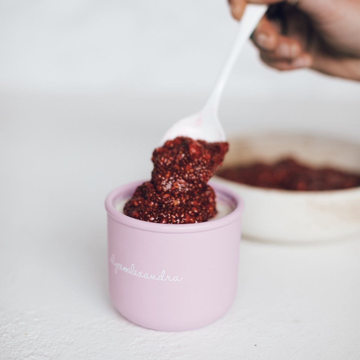 Hand spooning yoghurt into a pink Mini Silicone Pot Container