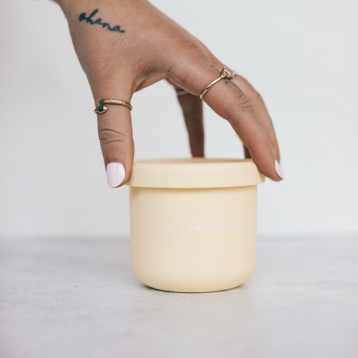 Hand lifting the lid from a yellow Mini Silicone Pot Container