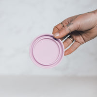 Hand holding the pink lid of a Mini Silicone Pot Container to show its seal