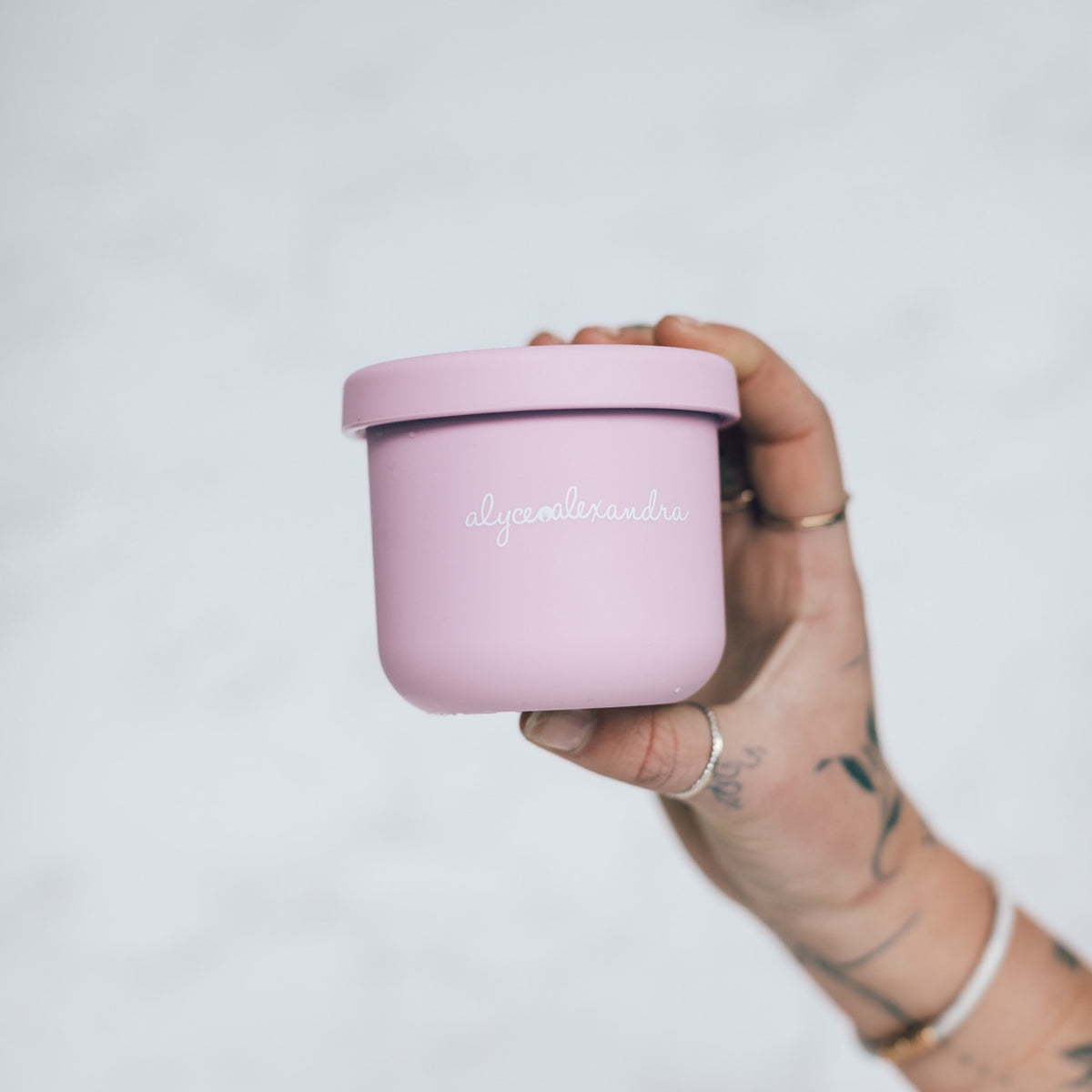 Hand holding a pink Mini Silicone Pot Container with the lid on